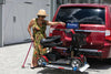 Woman securing a red scooter on a Harmar AL300 (base model shown) behind a red minivan