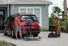 Man unfolding a Harmar AL300 (base model shown) behind a red minivan while a woman waits with a scooter