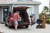 Man loading the minivan's cargo area with a Harmar AL300 (base model shown) folded on the hitch