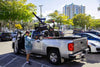 Man using a Harmar AL815CC (base model shown) to lift a scooter into a silver pickup truck bed