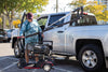 Man guiding a scooter beside a pickup truck as a Harmar AL815CC (base model shown) lifts it