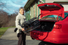 Woman lifting a folded Feather Chair into a car trunk