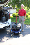 Man standing beside a power wheelchair lowered by a Bruno VSL-6900 Curb-Sider at the back of an SUV