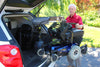 Man guiding a power wheelchair as a Bruno VSL-6900 Curb-Sider lifts it out of an SUV