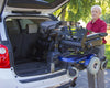 Bruno VSL-6900 Curb-Sider holding a power wheelchair at the rear of an SUV while a man guides it