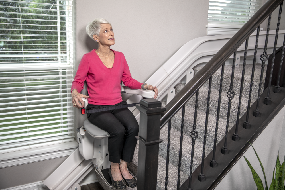 Woman using a stairlift in a home setting