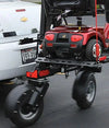 Red scooter secured on the Bruno Chariot behind a car