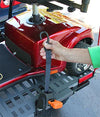 Hand tightening a strap that holds a red scooter on the Bruno Chariot platform