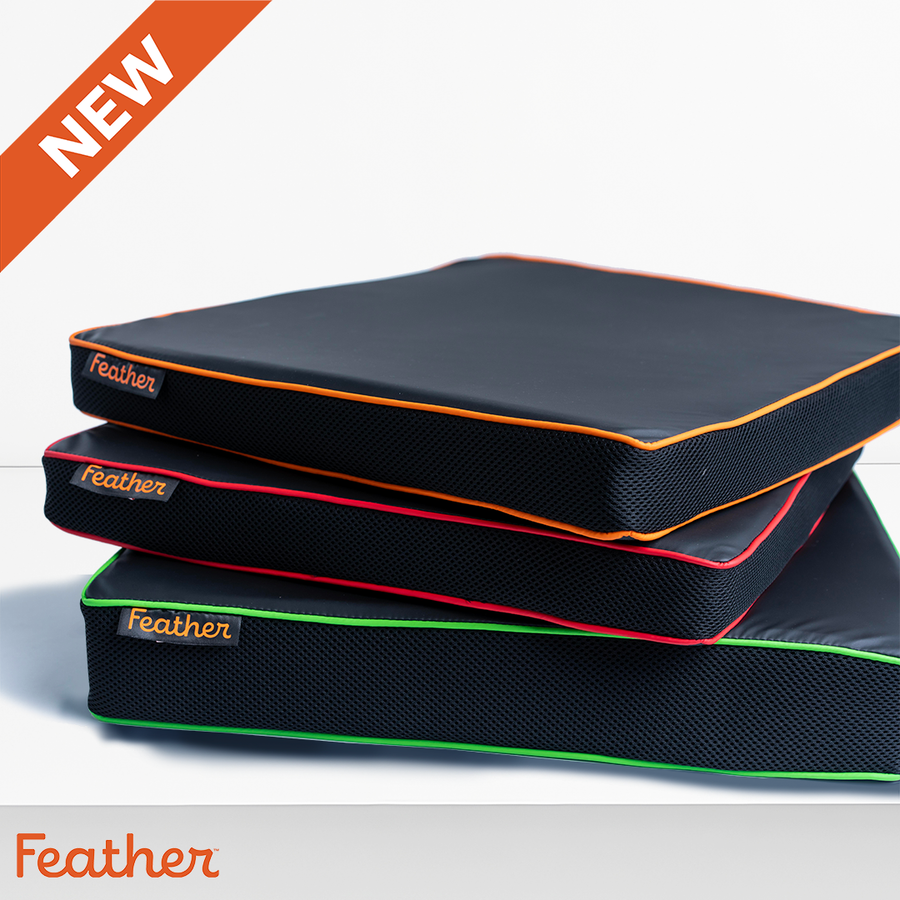 Three Feather wheelchair cushions stacked, black with orange, red and green trim