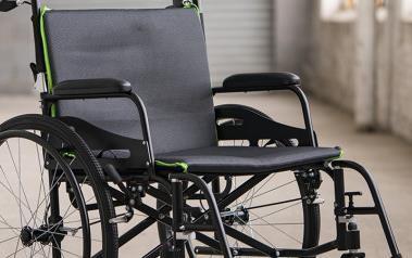 Black wheelchair seat and back upholstery with green trim, fitted to a wheelchair