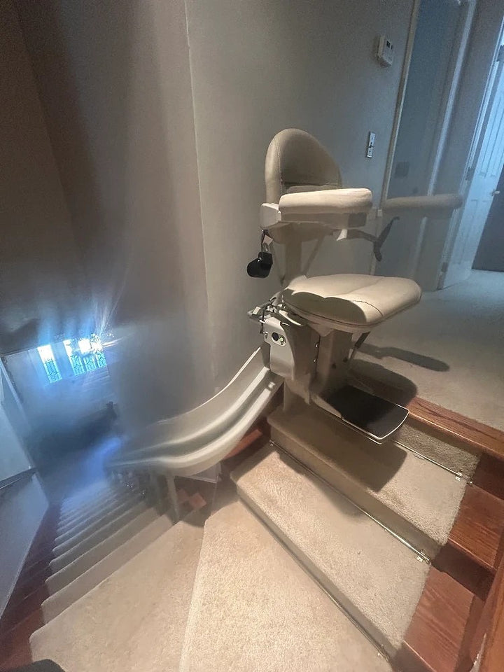 Bruno curved stairlift on a rail turning around the bottom of a carpeted staircase