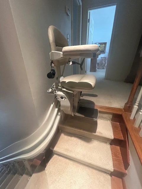 Bruno curved stairlift parked at the bottom turn of carpeted stairs beside a doorway