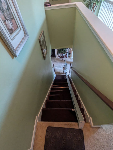 Bruno Elan stairlift rail on stairs leading down from a pale green hallway