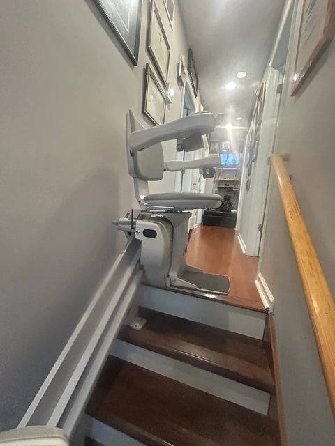 Bruno stairlift on a straight rail down a narrow staircase from an upstairs hallway
