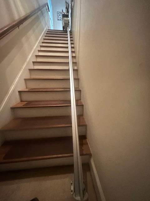Bruno stairlift rail on a long staircase with the chair parked at the top