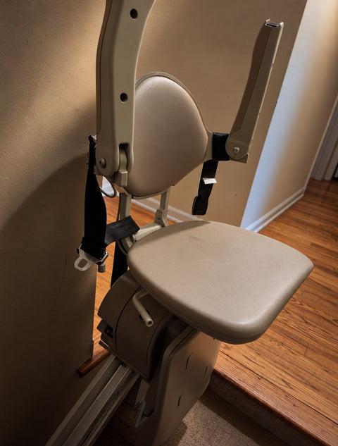 Bruno stairlift at the top of the stairs with the seat folded up and arms raised