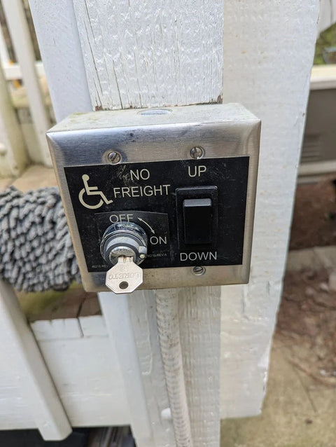 Harmar vertical platform lift call station with a key switch and up and down buttons on a post