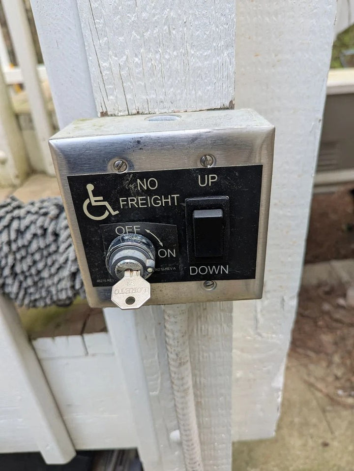 Harmar vertical platform lift call station with a key switch and up and down buttons on a post