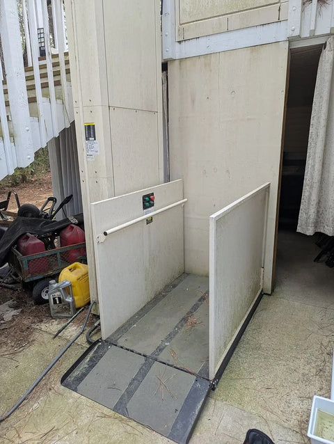 Harmar vertical platform lift beside a deck, its enclosure door open onto the platform