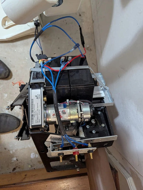 Handicare stairlift drive unit with motor and wiring exposed on a curved rail