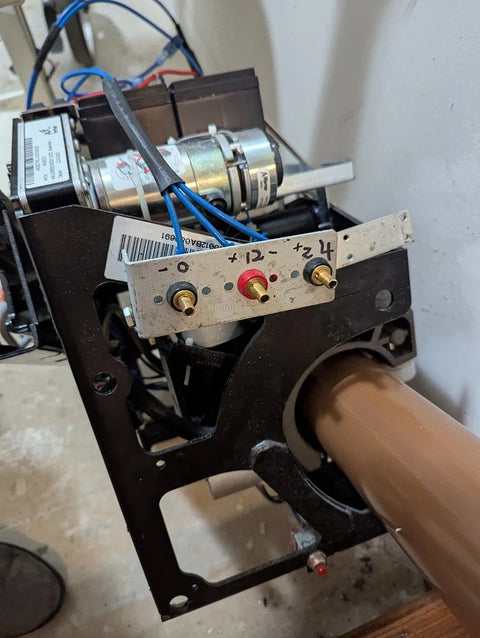 Handicare stairlift drive unit on a curved brown rail, side plate off for service