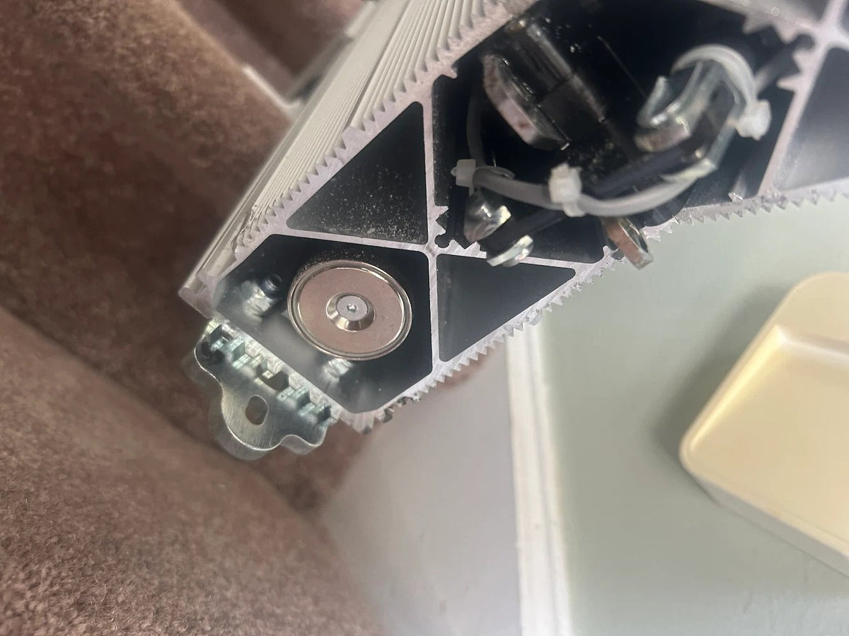 Handicare stairlift rail end with the drive gear and cabling exposed, close up