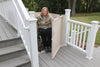 Woman in a wheelchair on a Bruno residential platform lift (VPL-3100/3200B series shown) opening the gate at the top of a deck