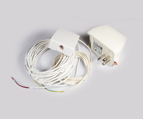 White plug-in transformer, a telephone-style wall jack and coiled white wiring with colored lead ends