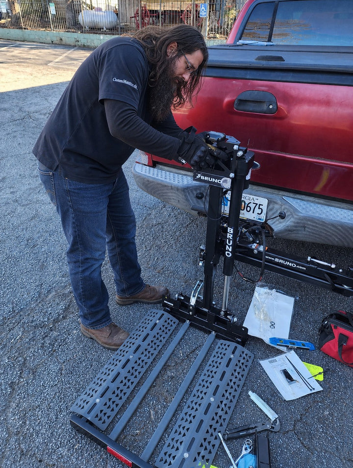 Mason Irby setting up a vehicle lift platform at the back of a red pickup truck